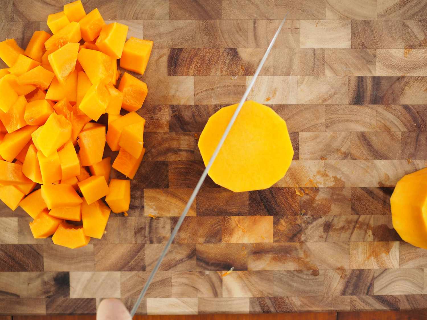 A round slice of butternut squash with a knife over it, indicating it's about to be cut up.