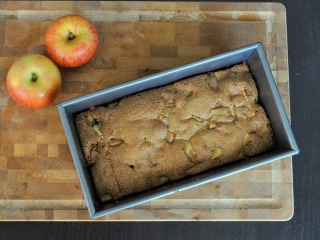 Overhead of a loaf of apple cinnamon quick bread in its pan on a cutting board.