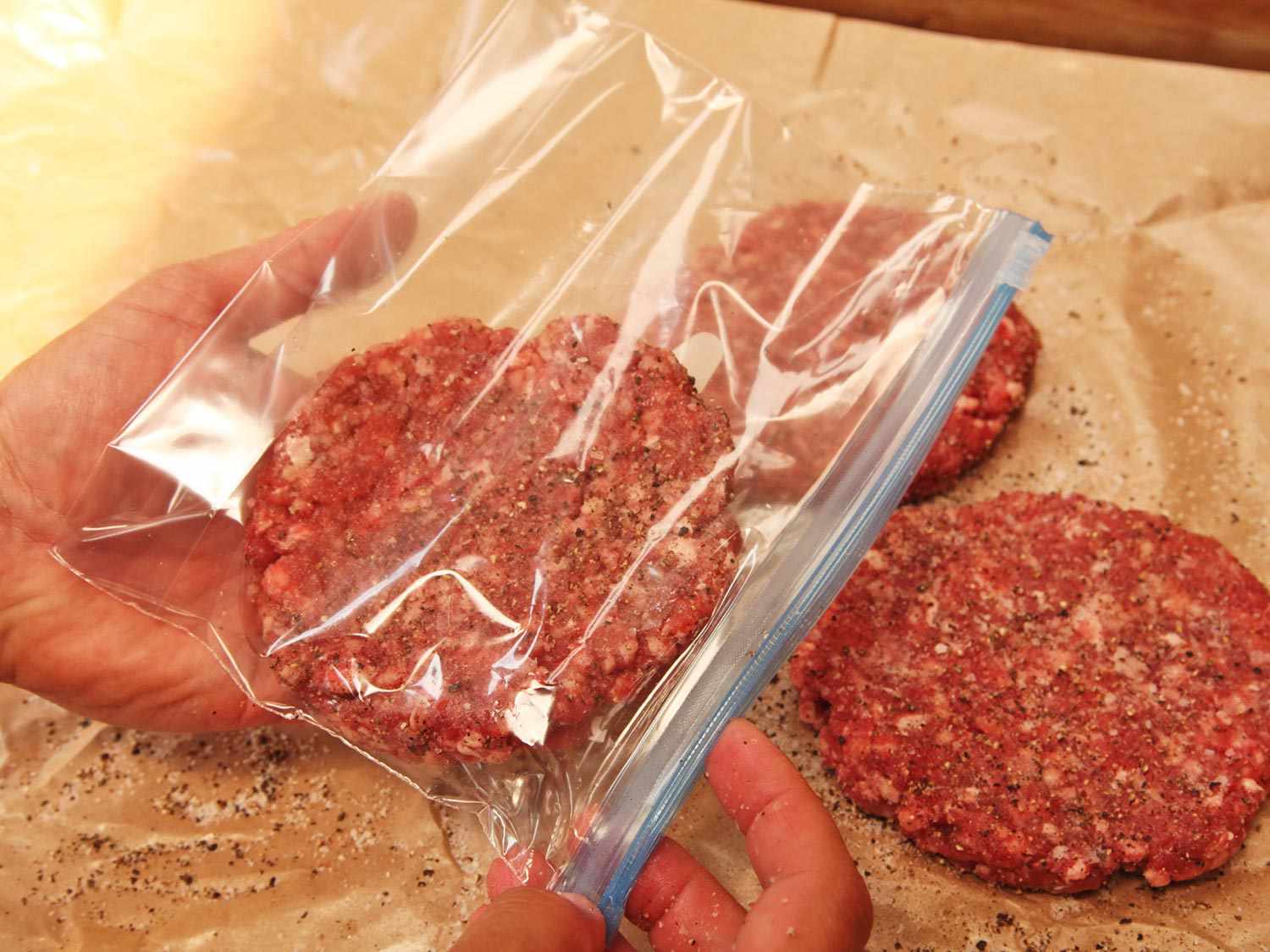 Placing a hamburger patty in a small zipper-lock bag before sealing via the displacement method and cooking sous vide.