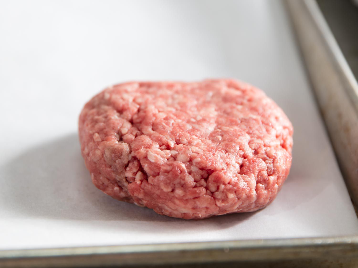 A raw burger patty on parchment paper