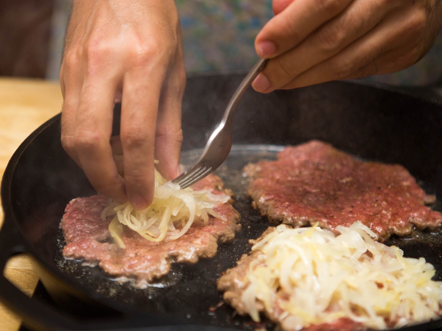 adding kraut to smashed burger patties