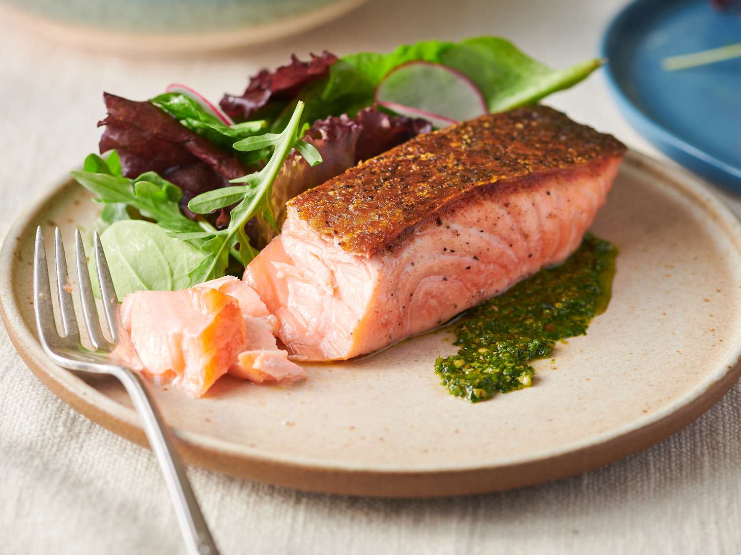 Crispy pan-seared salmon fillet served on a plate with greens