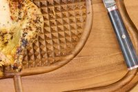 Roasted chicken on a Lipper International Acacia Cutting Board with Grid Grip with a knife in view