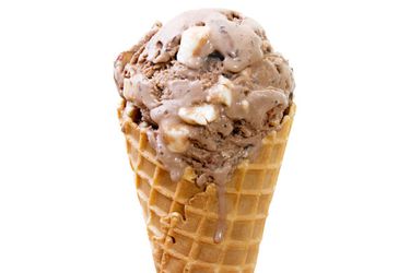 Profile view of a scoop of rocky road ice cream served in a waffle cone.