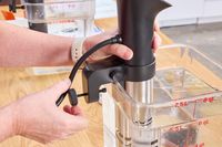 A person secures the Anova Culinary Precision Cooker Pro to the side of a container