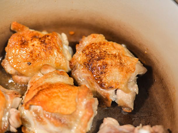 Chicken thighs are browned in a Dutch oven.