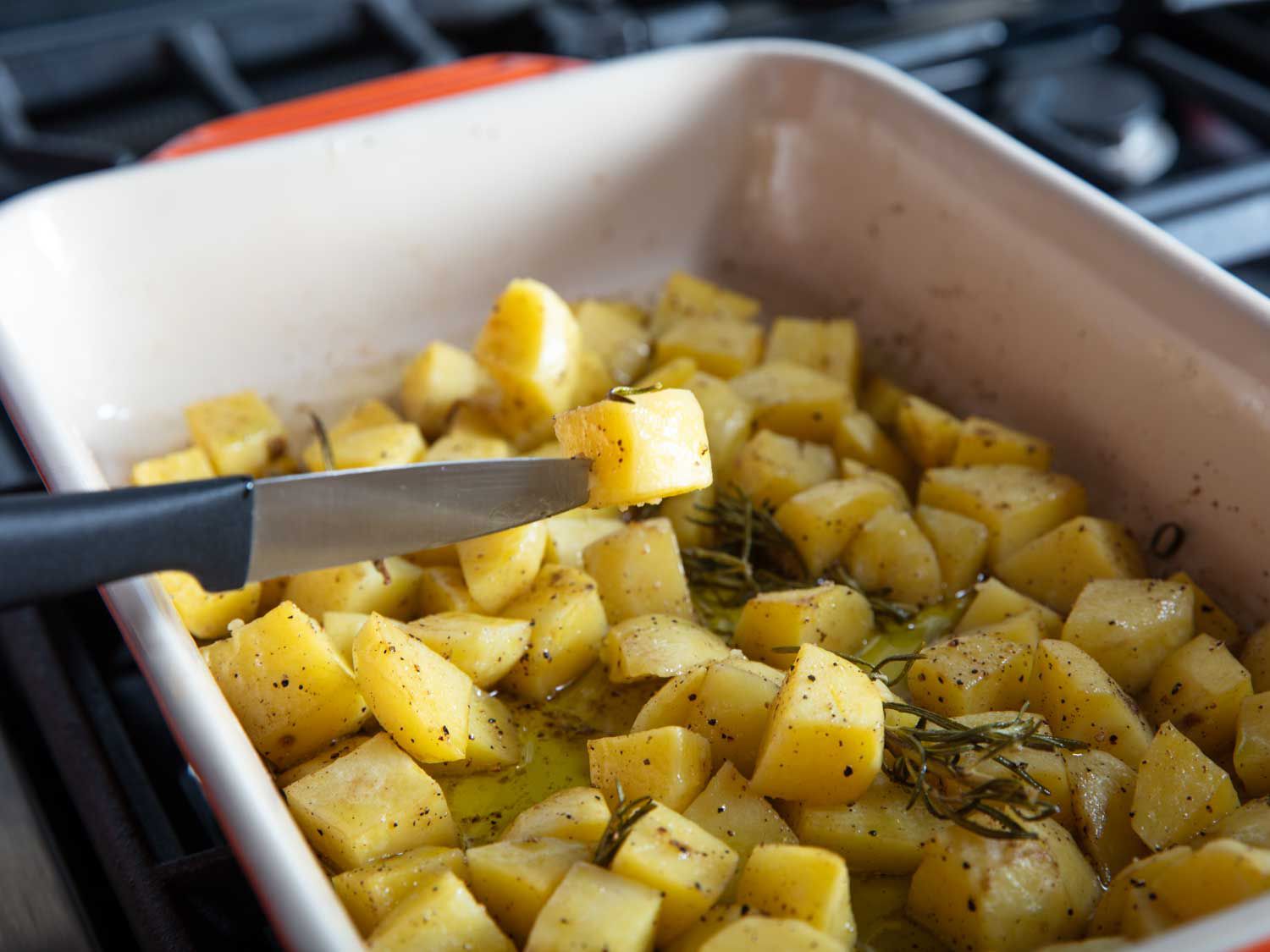 Piercing a knife through a potato piece to check its doneness. 
