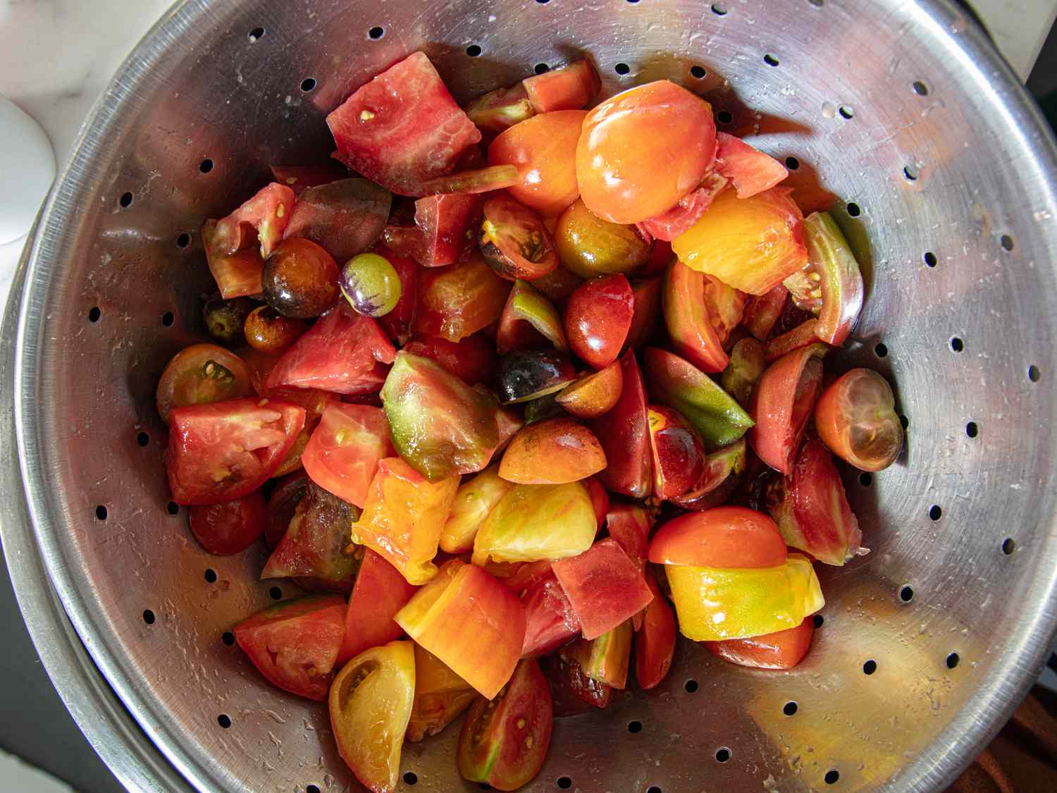 Chopped tomatoes in a colander preparation step for a dish likely a salad