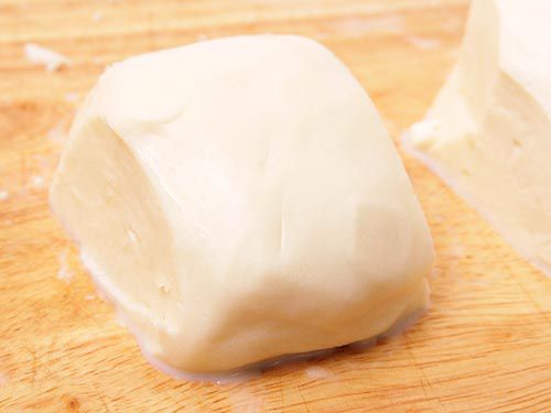 A chunk of wet mozzarella resting on a cutting board.