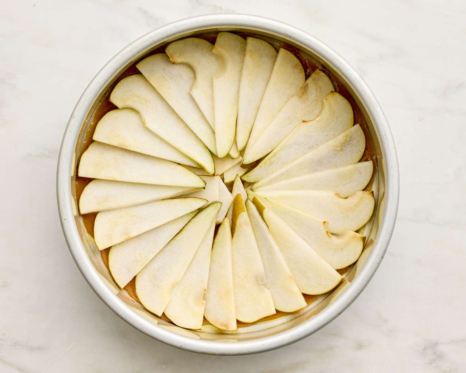 Slices of pears arranged in a circular pattern in a baking pan