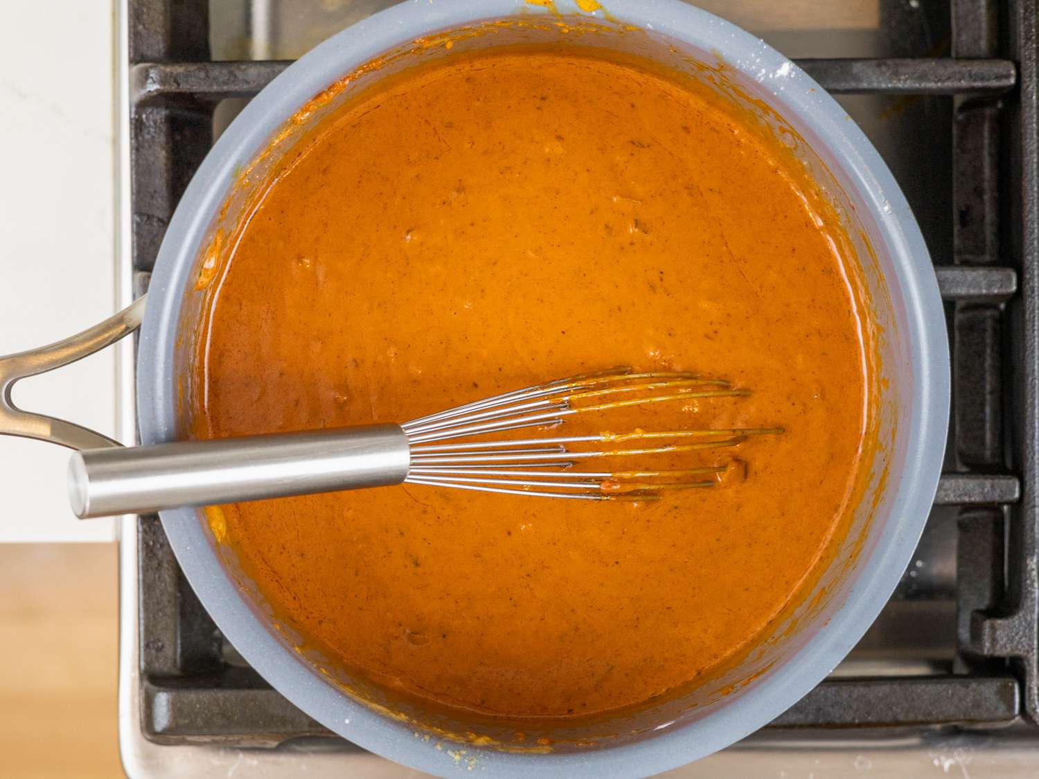 Kare kare sauce in a saucepan with a whisk