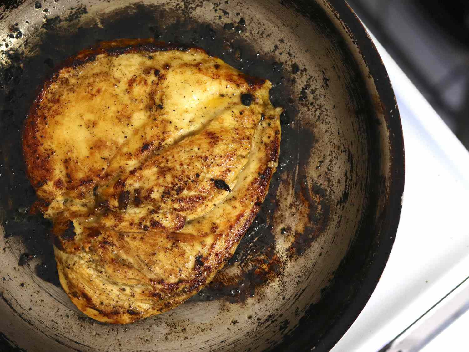 Seared boneless marinated chicken breasts in a skillet.