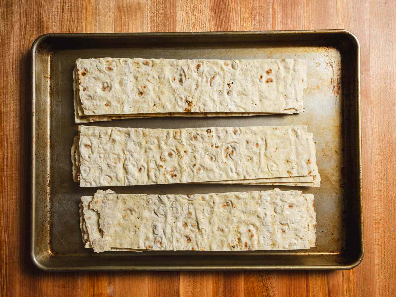 Lavash strips on a rimmed baking sheet.