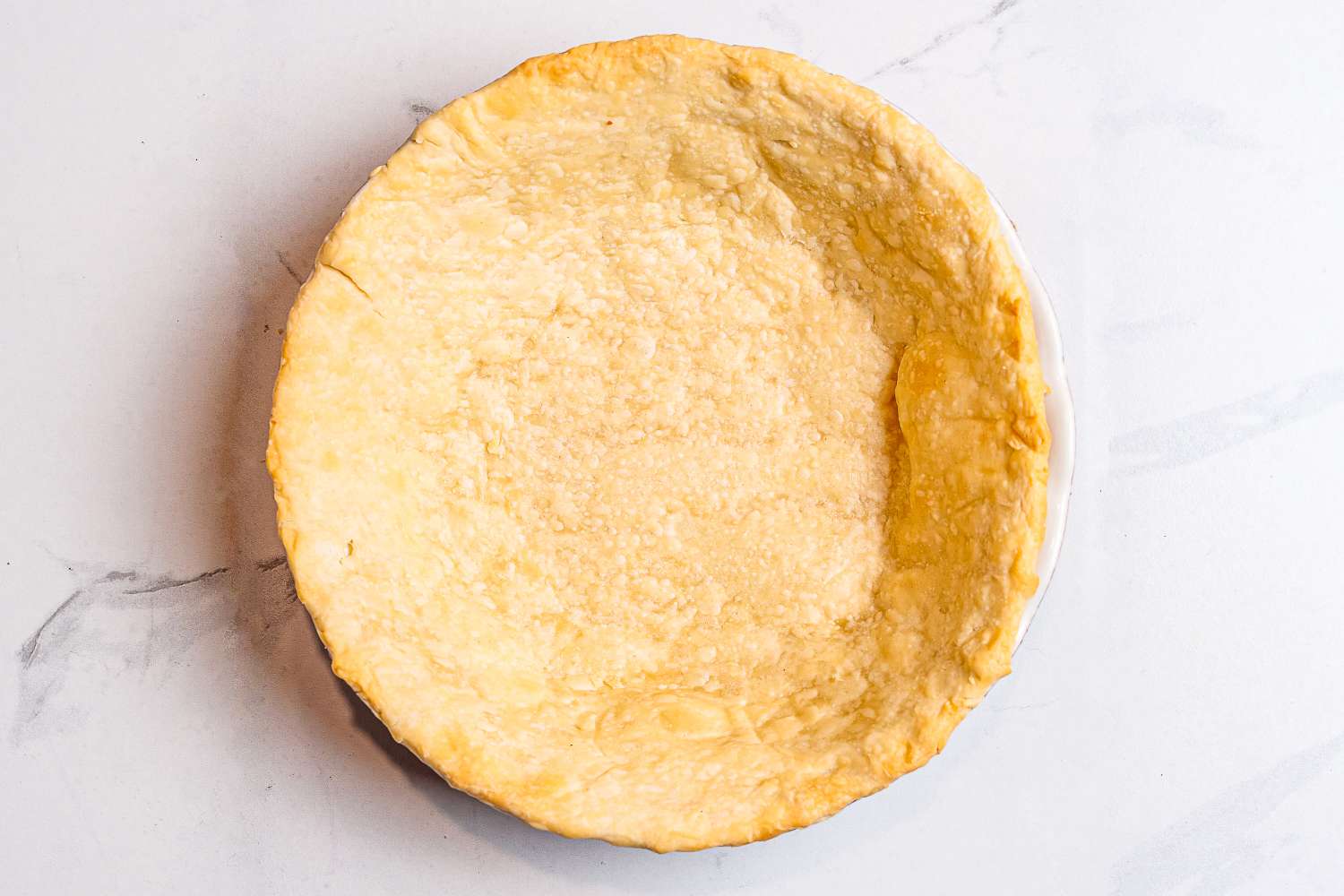 A baked pie crust in a Emile Henry Modern Classics Pie Dish viewed from above