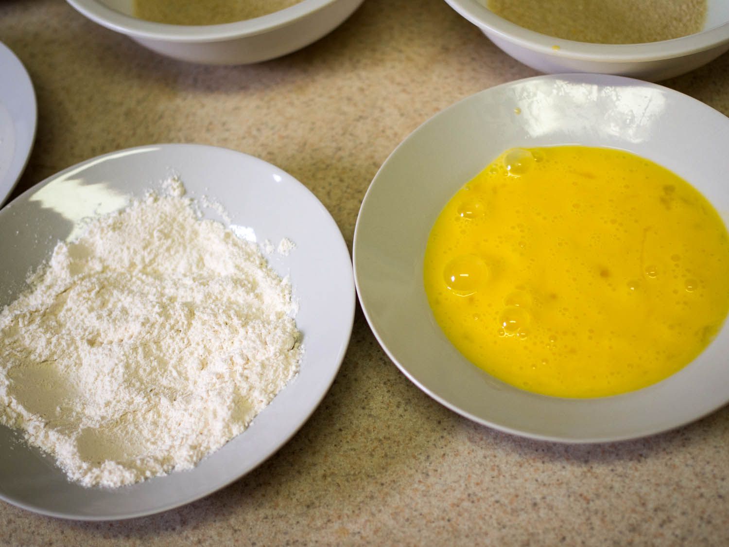 Two shallow bowls. One contains flour, the other beaten eggs.