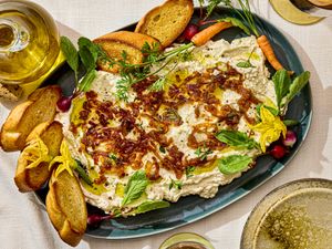 Platter of whipped ricotta dip garnished with herbs and served with toasted baguette slices