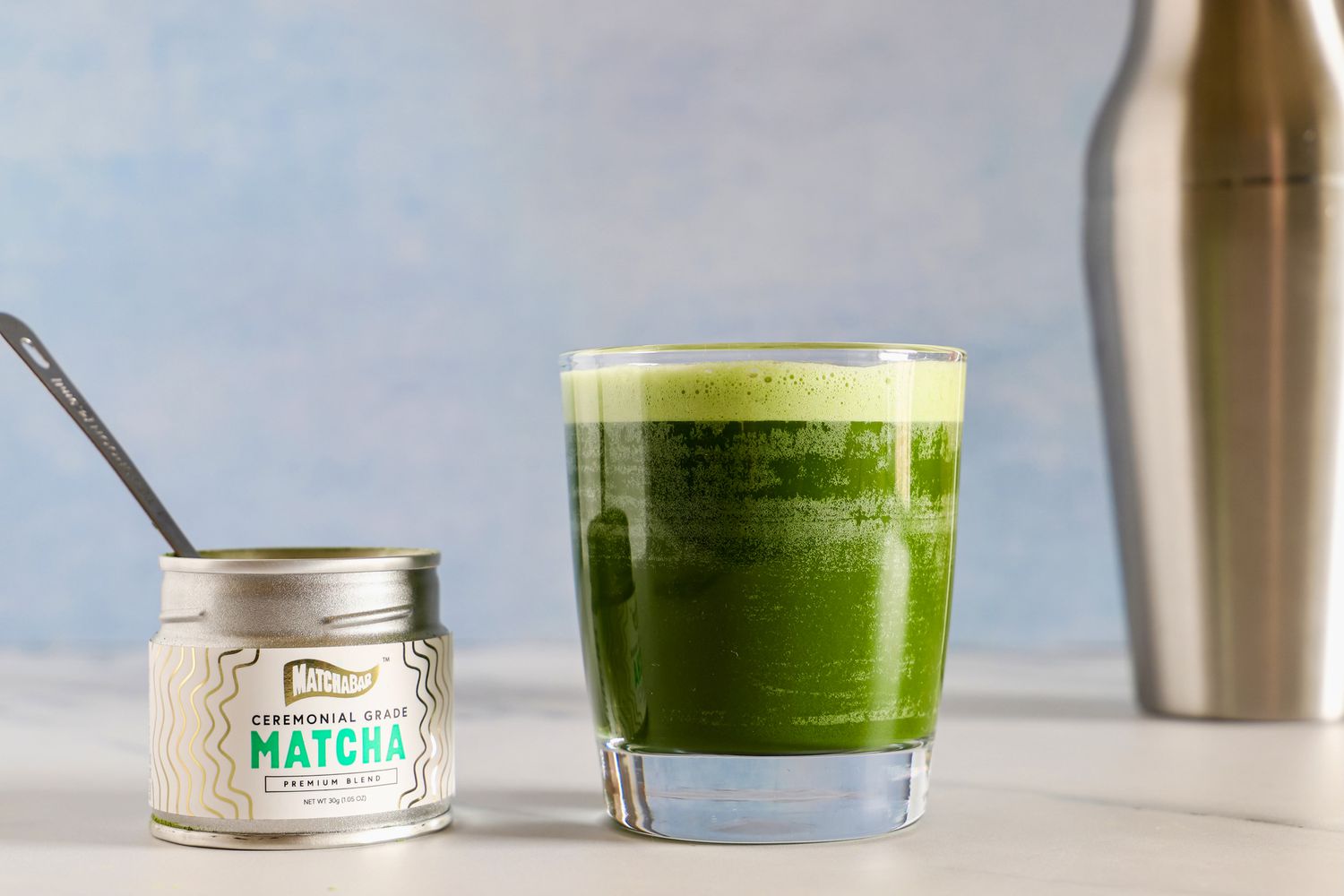 A glass of Matcha Bar Premium Blend next to the container