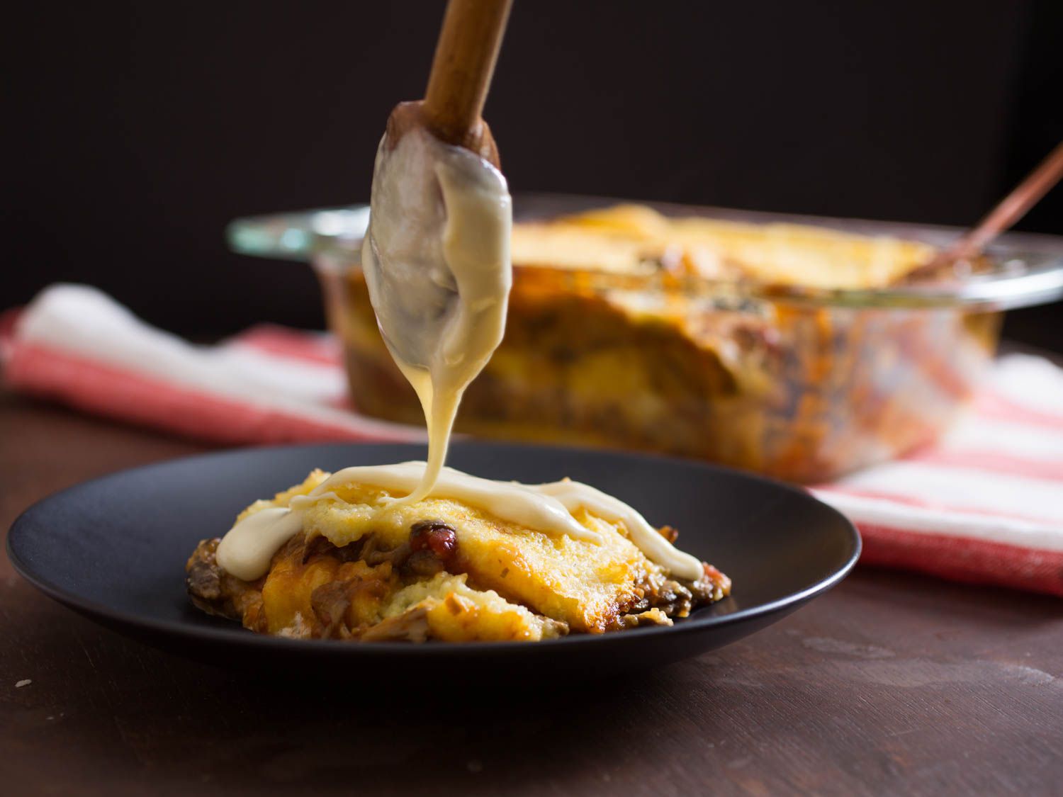 A plated serving of polenta lasagna is drizzled with Parmesan cream.