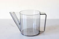 A transparent measuring cup with markings in milliliters and cups featuring a spout and handle