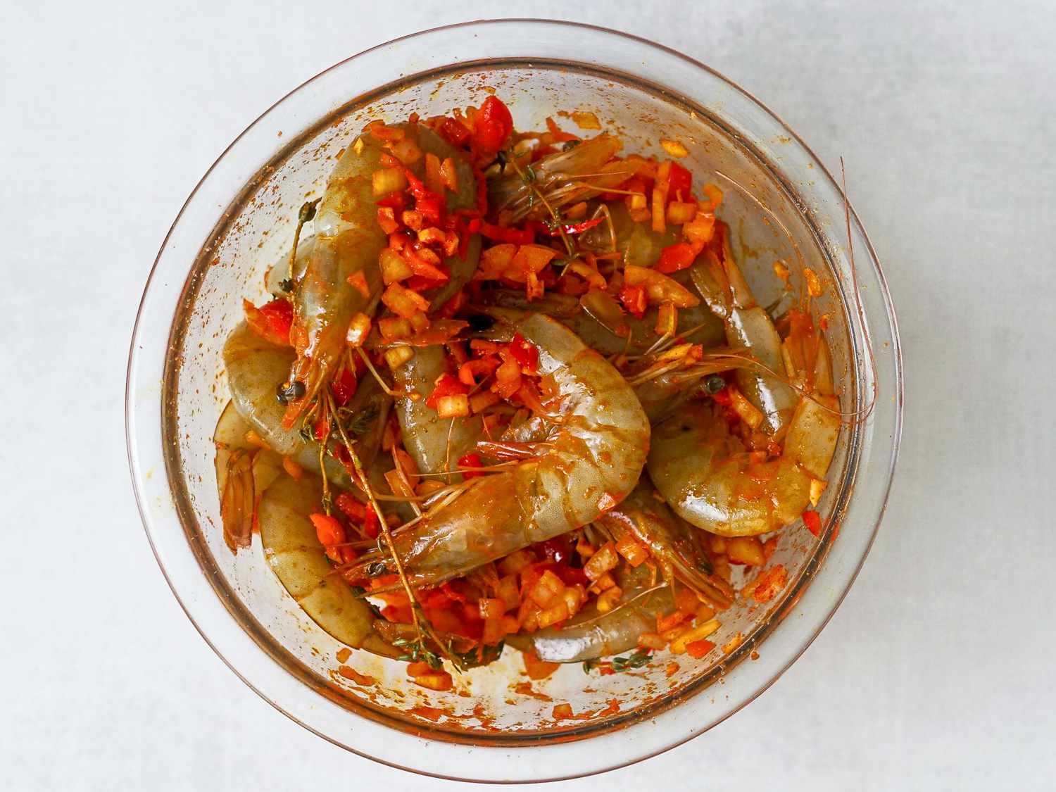 Shrimp mixed in with peppers and spices in a bowl.