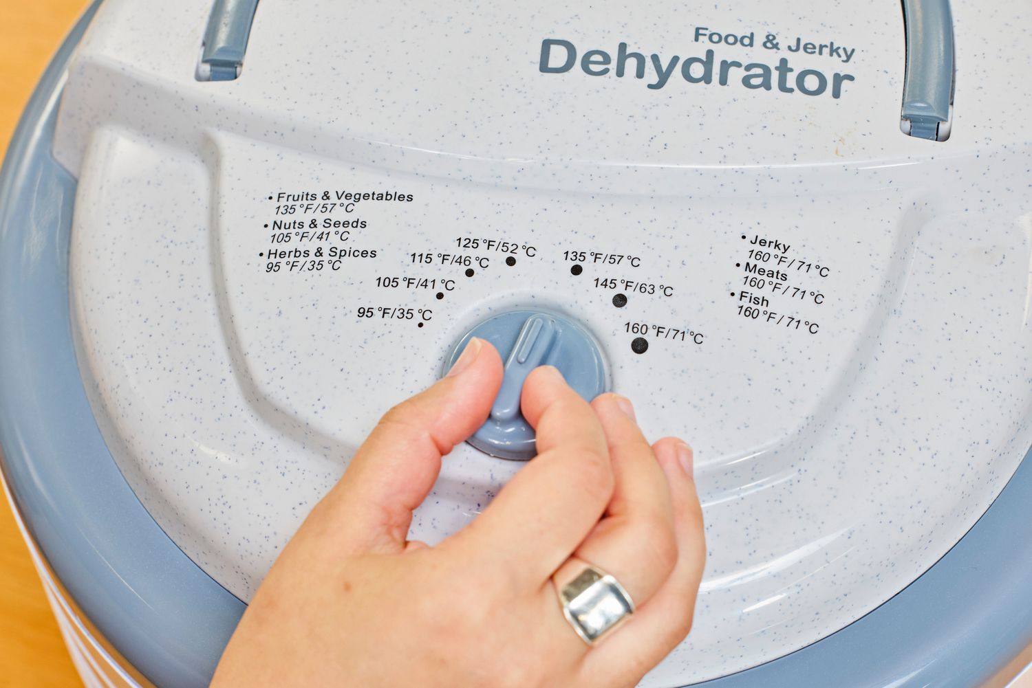 A person rotating the knob of Nesco Snackmaster Pro Food Dehydrator