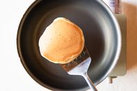 Using a metal spatula to flip a pancake in a pan
