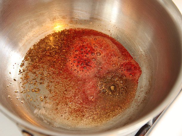 Toasting achiote, cumin, and oregano in oil in a stainless steel sauce pan 