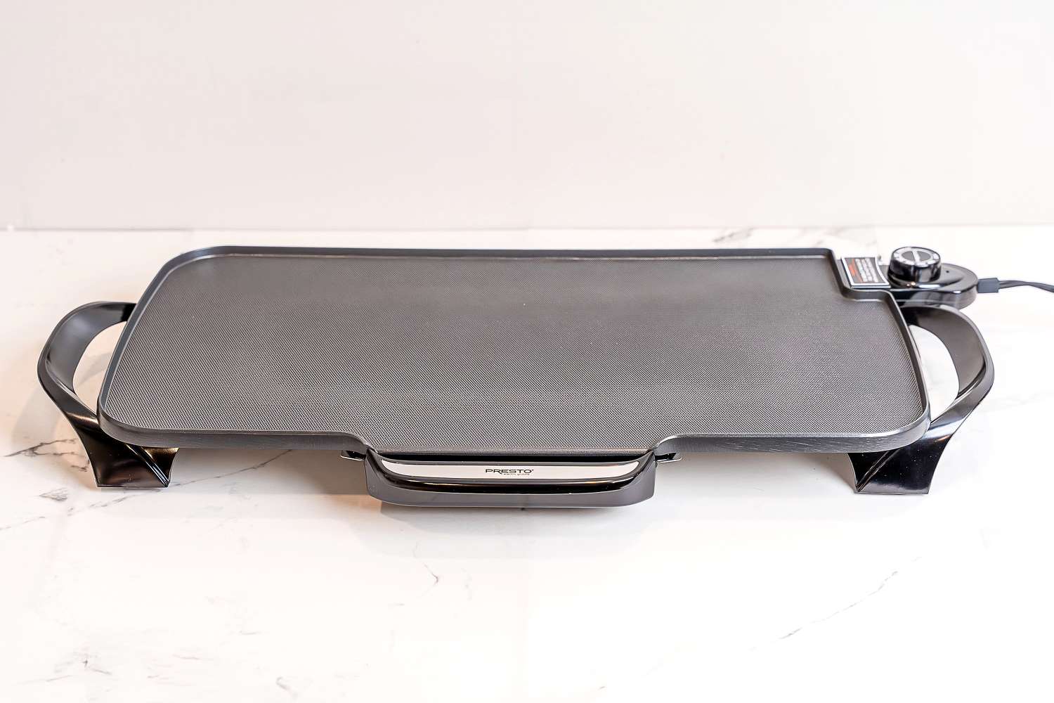The Presto electric griddle on a white marble countertop