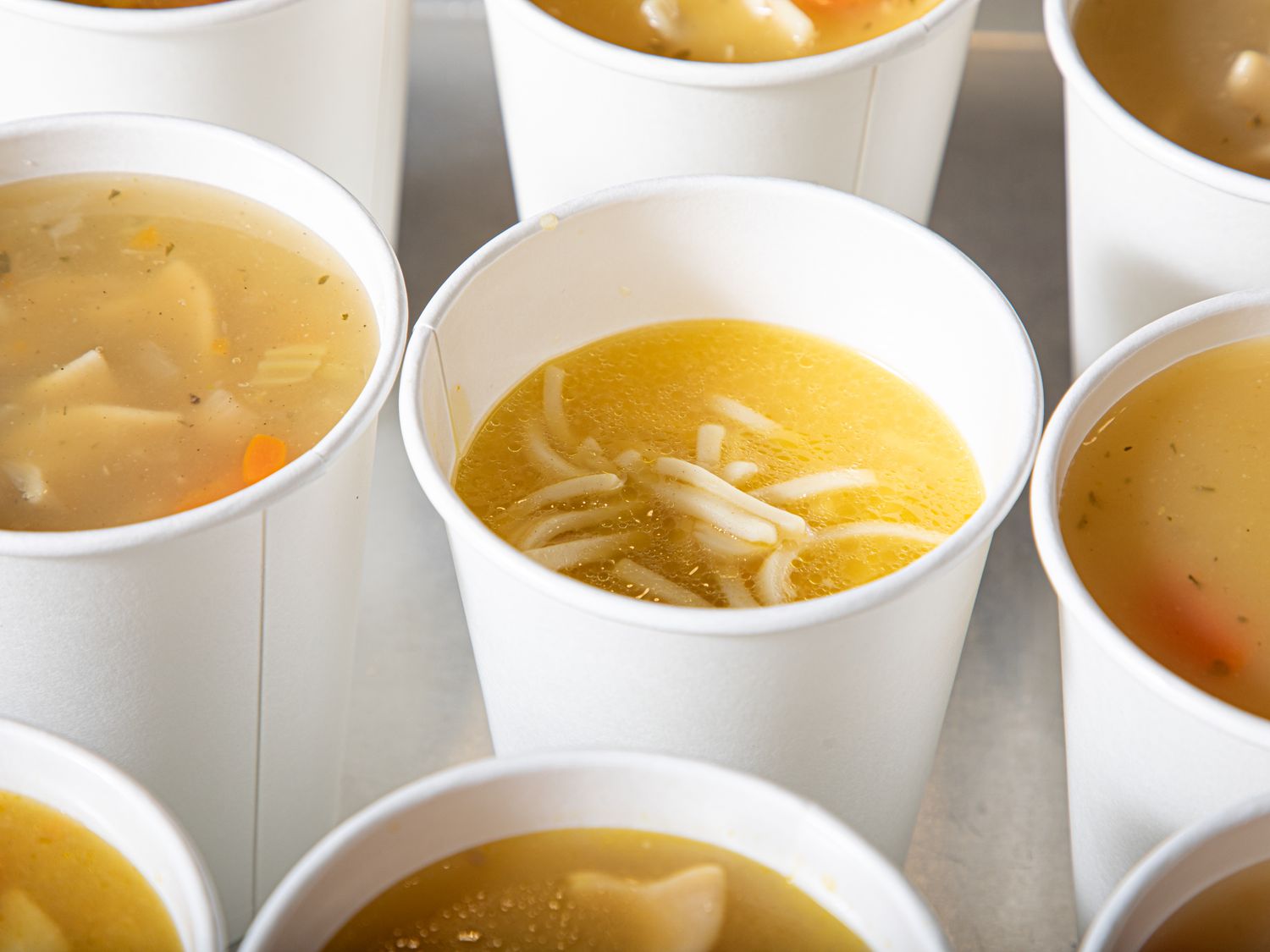 Several cups of chicken noodle soup arranged on a table