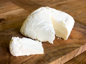 A cut of queso fresco resting on a cutting board