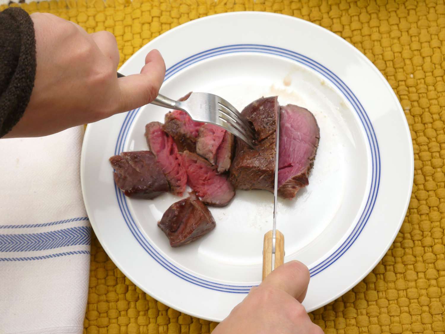a person using the made in steak knife to slice steak
