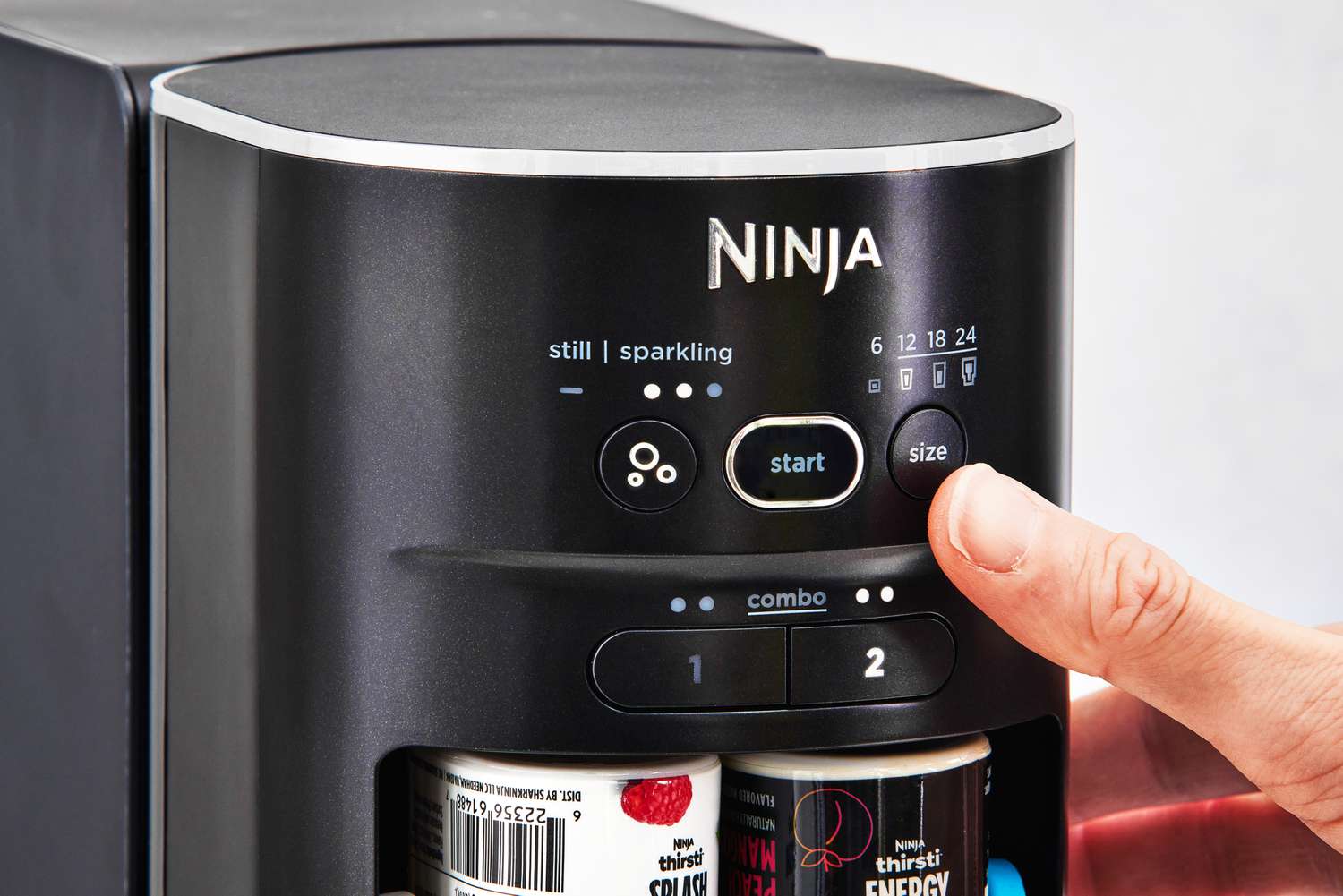 Closeup of a finger pressing a button on Ninja Thirsti Drink System