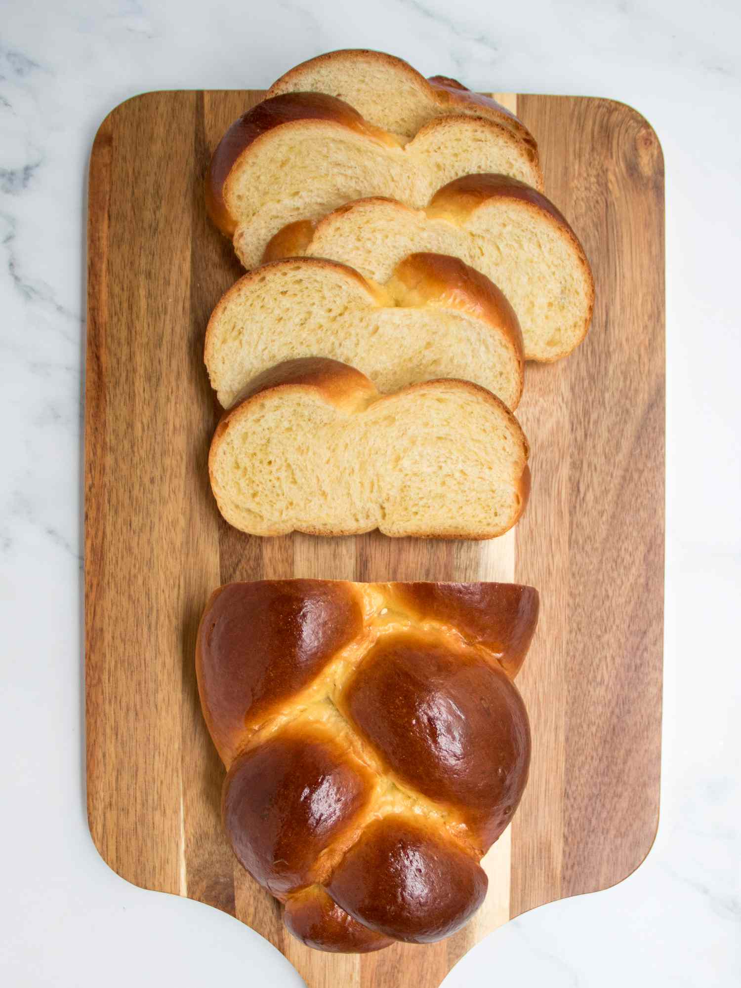 Half sliced loaf of challah on a wood board