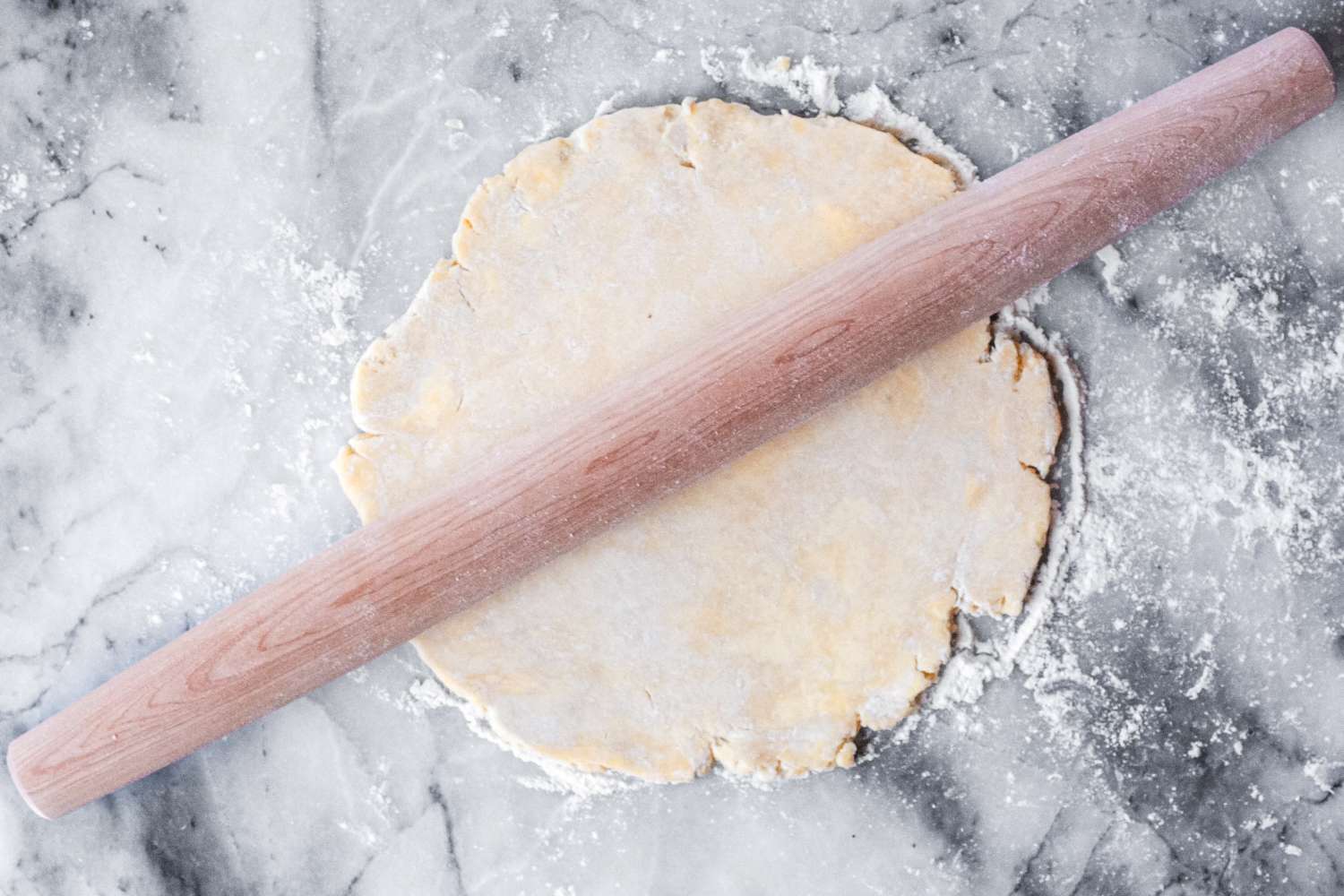 A J.K. Adams Maple French Rolling Pin on rolledout dough on a floured surface