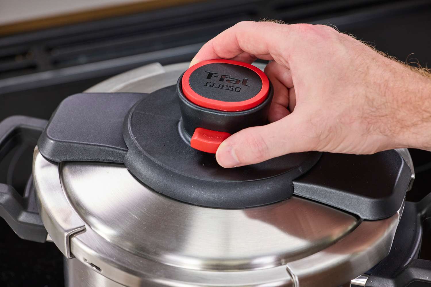 A person unlocks the lid of the T-Fal Clipso Pressure Cooker