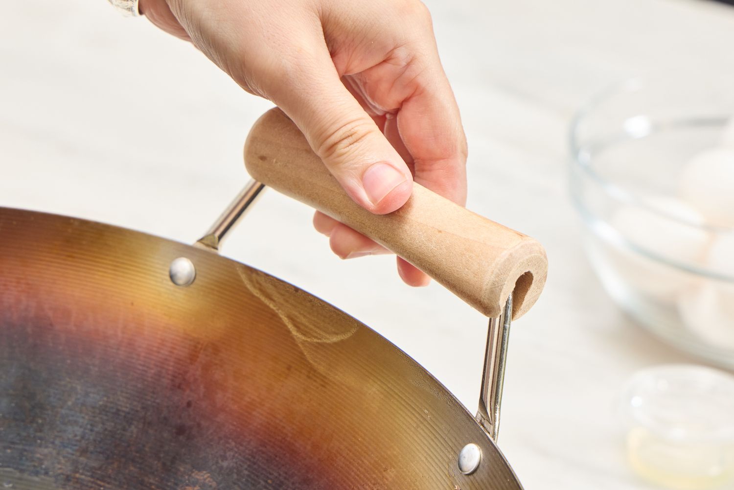 A person holds the handle of the Joyce Chen Carbon Steel Wok