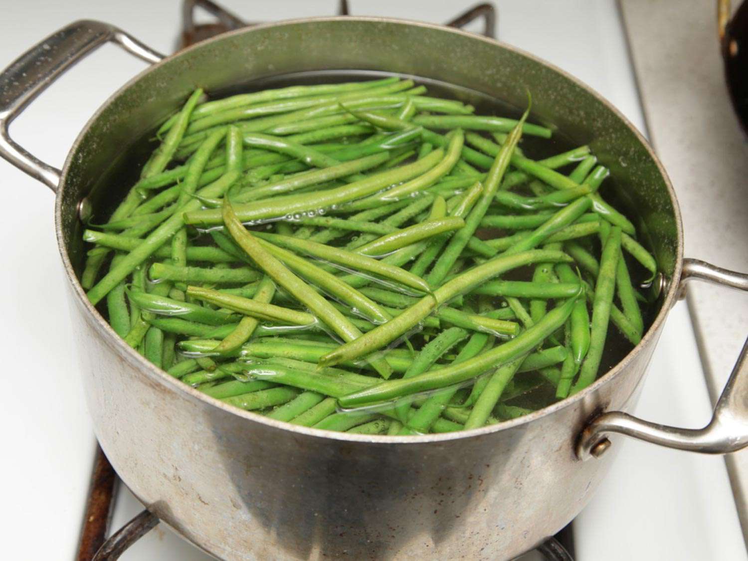 Green beans blanching in a pot of water.
