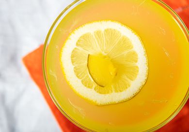 A mezcal pickle lemonade garnished with a slice of lemon and pickle piece top view