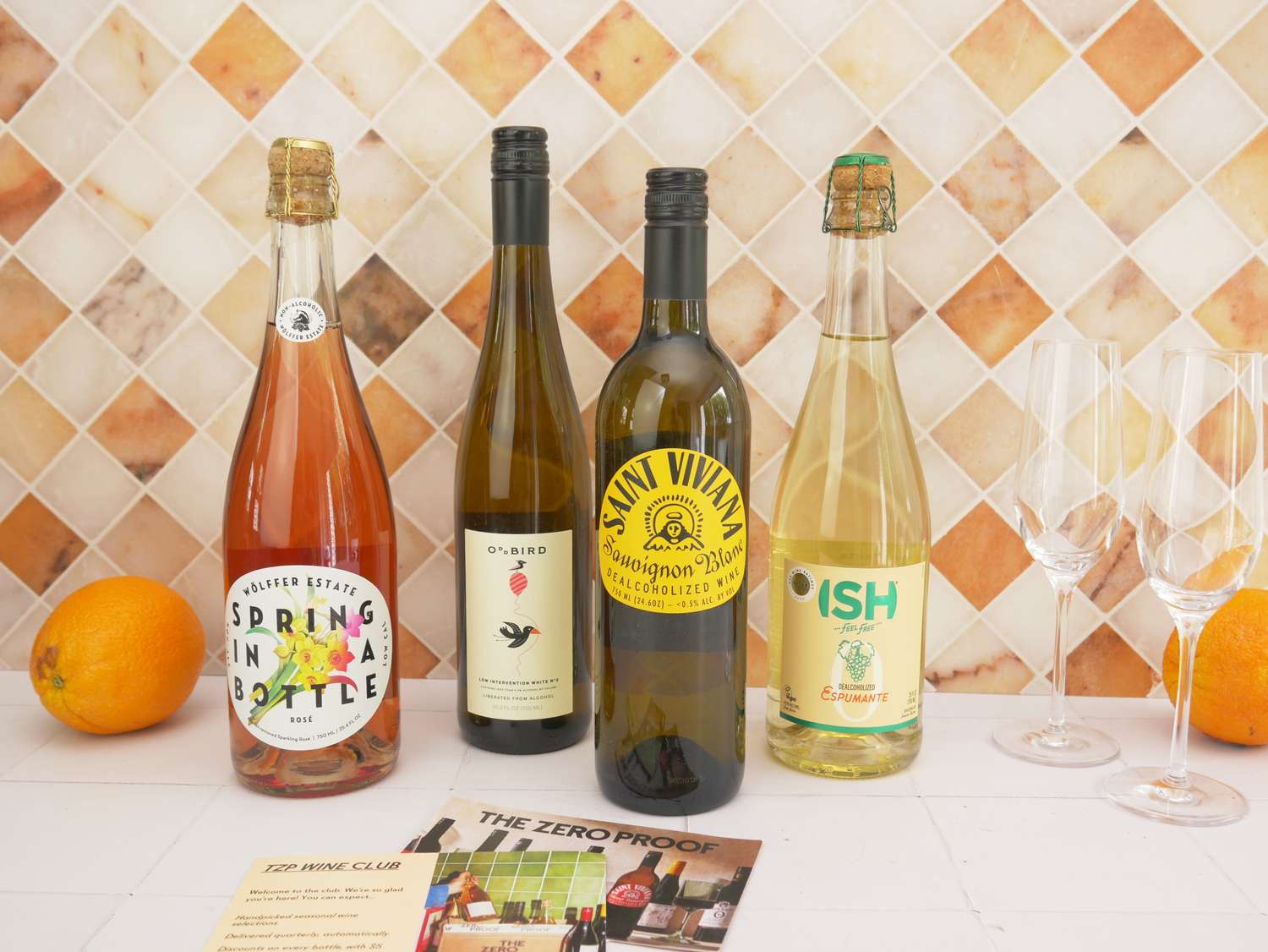 four bottles of NA wine with two flute glasses