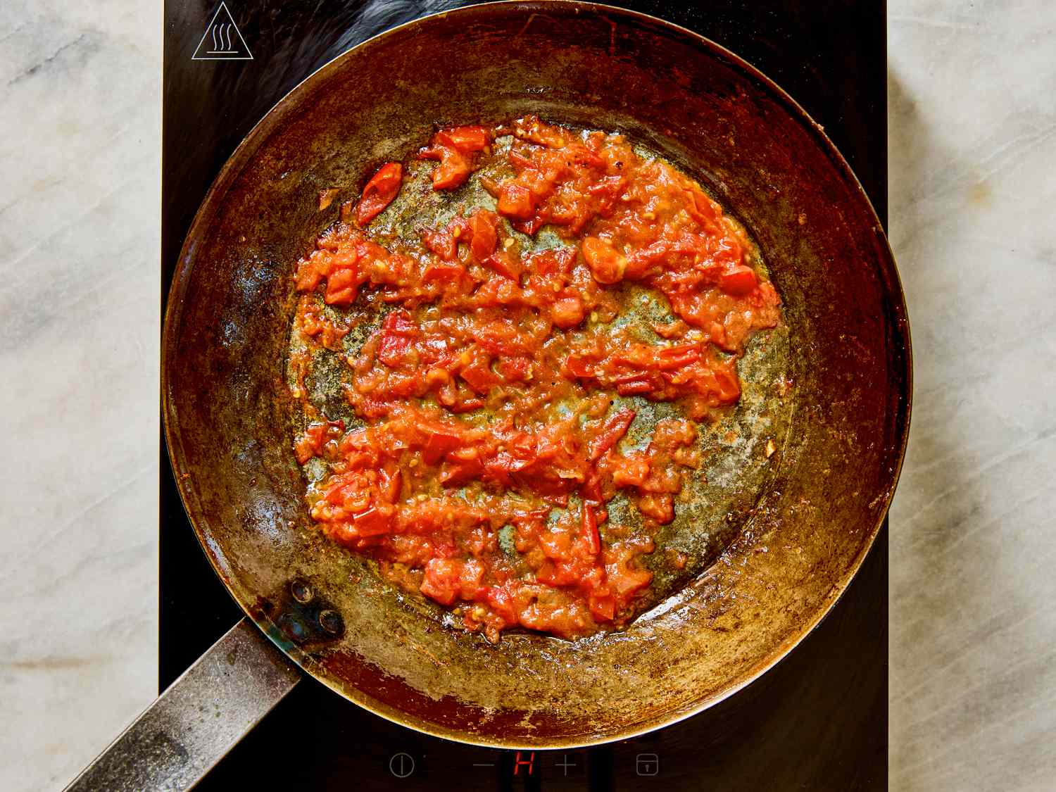 Frying pan containing cooked tomato sauce on a stovetop