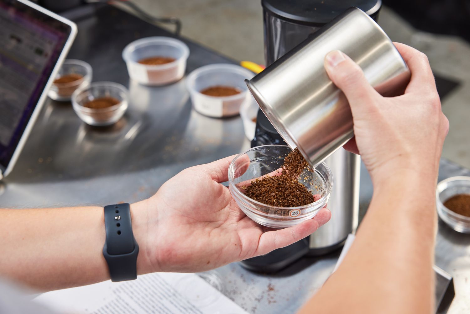 Person's hand pouring ground coffee into a bowl after grinding beans using the OXO Brew Conical Burr Coffee Grinder
