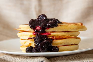 A stack of lemon ricotta pancakes topped with a blueberry compote