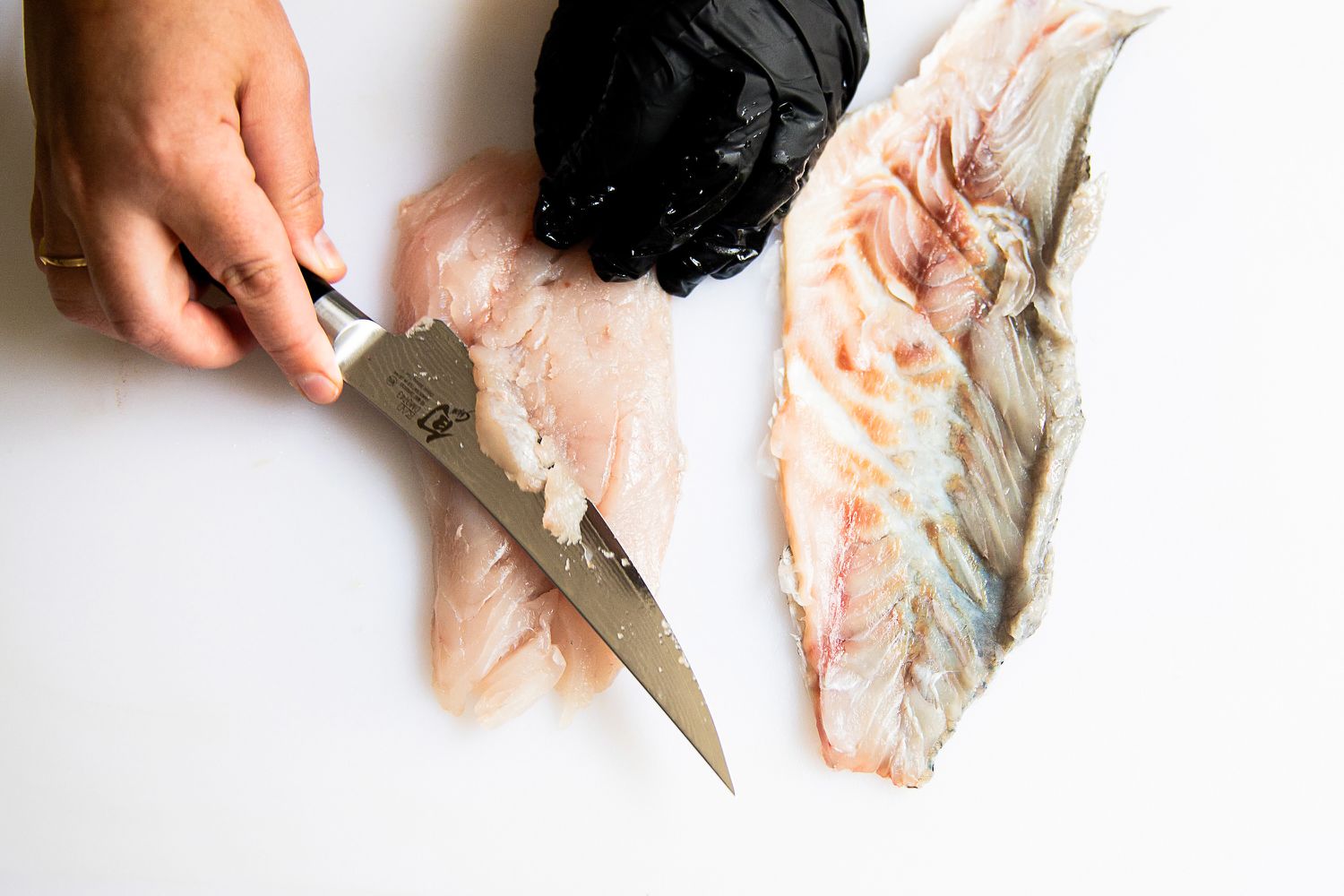 A person using the Shun Classic 6" Boning & Fillet Knife to slice a fish