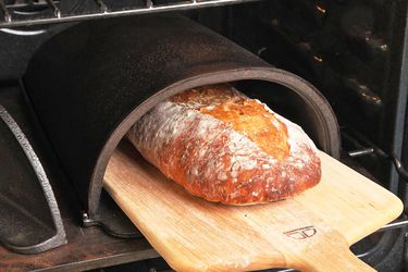 Removing a loaf of bread from a Forneau bread oven with a wood peel. 