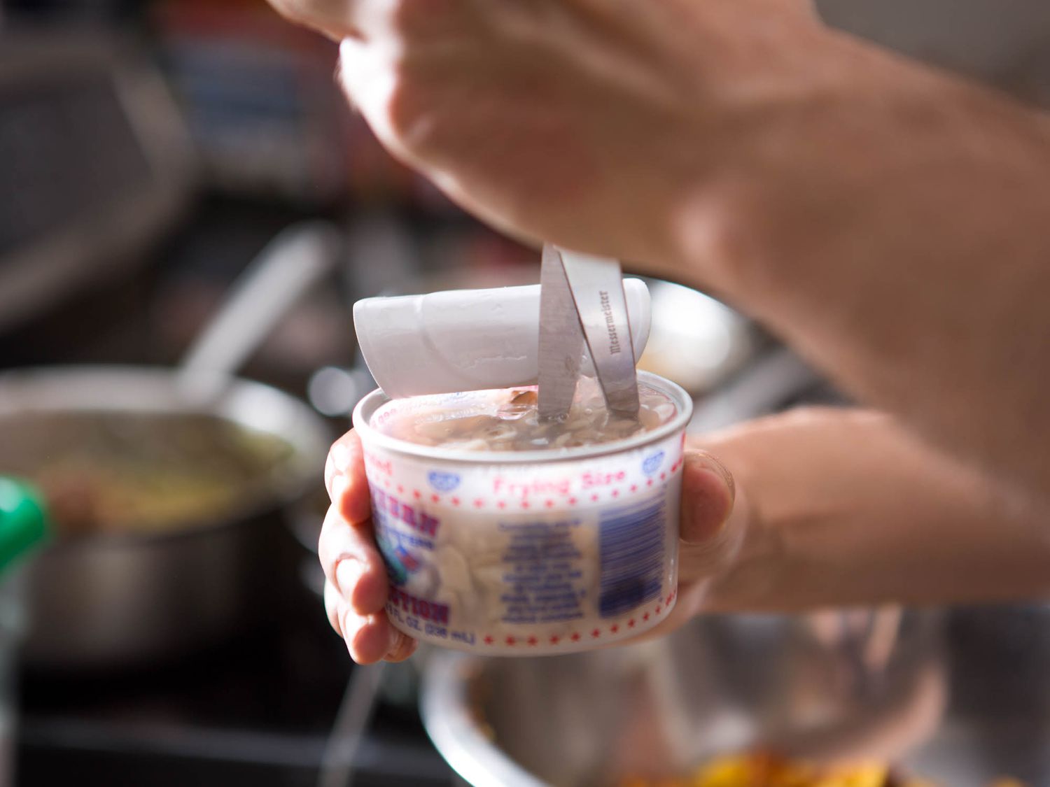 Using kitchen shears to cut the oysters right in their container.