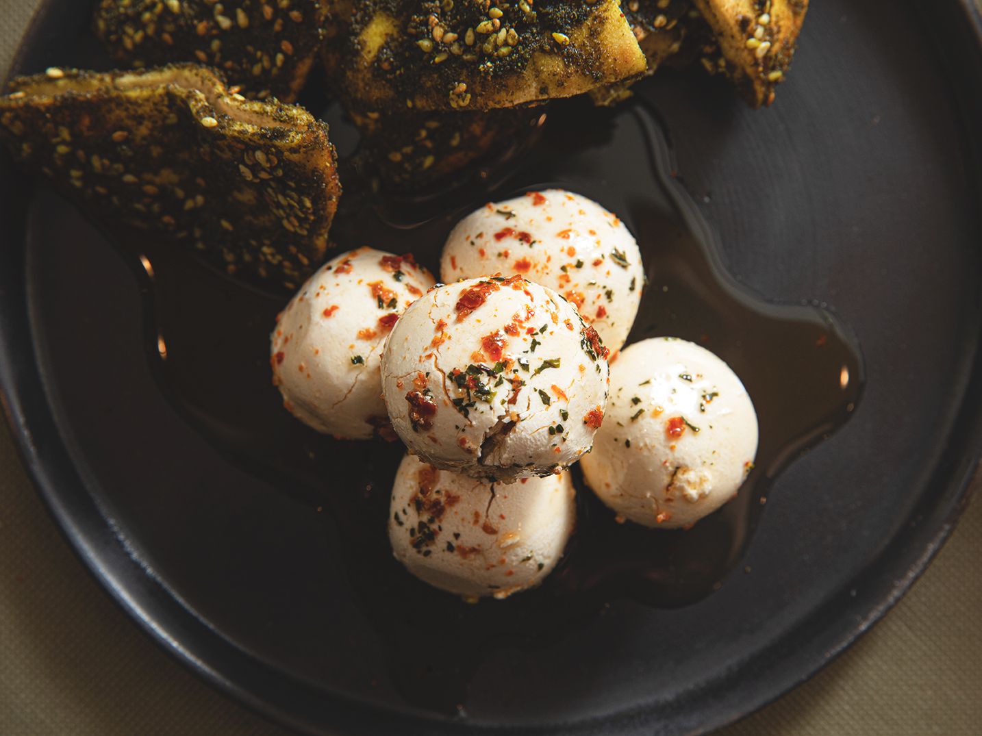 Labneh rolled into balls on a plate next to pita chips