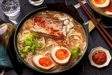 A bowl of ramen with pork softboiled eggs green onions and toppings