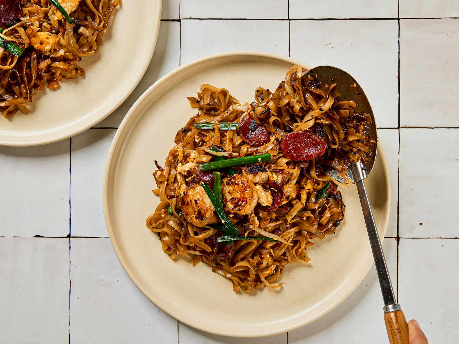 Char kway teow served on plates with a utensil