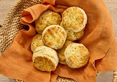 sour cream and chive biscuits in a basket with an orange napkin