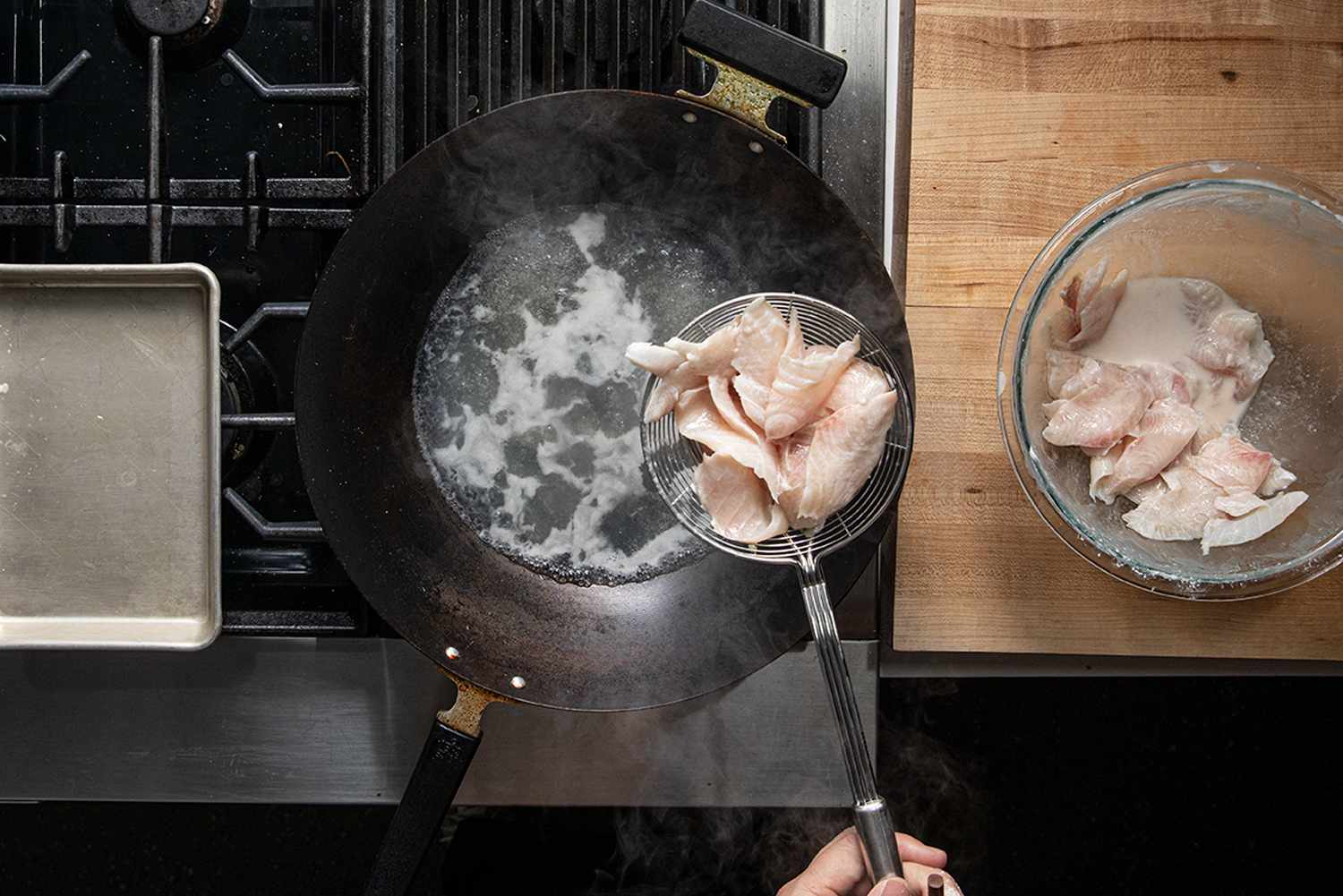 Overhead fish of fish being passed-through water in a wok.